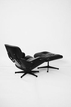 an eames chair and ottoman in black leather on a white background with the foot rest extended