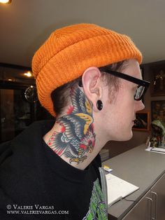 a man with a dragon tattoo on his neck is wearing an orange beanie hat