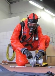 a man in an orange suit is working on a piece of equipment