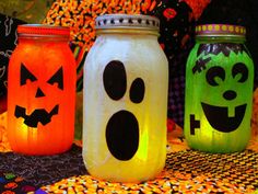 three mason jars decorated to look like jack - o'- lanterns with faces on them