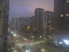 a city street filled with lots of traffic under tall buildings in the distance at night