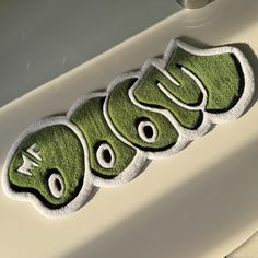 the word moo spelled out in green letters on top of a white sink drain