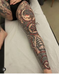 a woman with tattoos on her leg and arm sitting on a bed next to another person