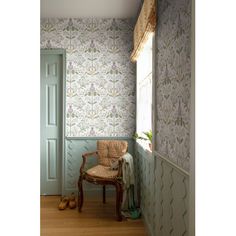 a chair sitting in front of a window next to a wallpapered room with flowers on it