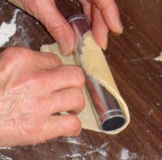 a person rolling out dough on top of a wooden table