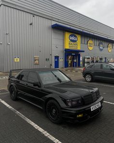 a black car parked in front of a building with two cars next to each other