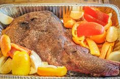 a roast beef with vegetables and potatoes in a tin container on a wooden table top