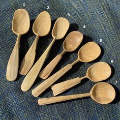 six wooden spoons are lined up next to each other on a blue carpeted surface