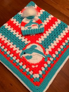 a red, white and blue crocheted afghan with a pom - pom on top