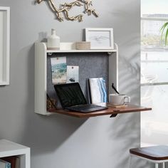 a laptop computer sitting on top of a wooden shelf