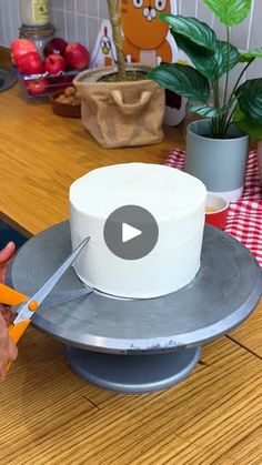 a person cutting a cake with a pair of scissors on top of the cake plate