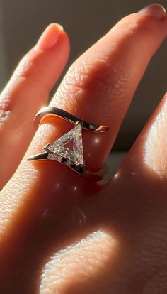 a woman's hand with a diamond ring on top of her finger and an orange background