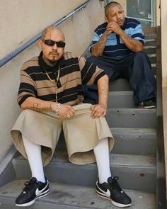 two men sitting on the steps with their arms crossed and one man wearing sunglasses is holding his hand up to his mouth