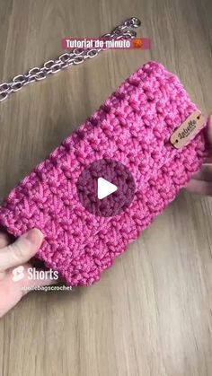 someone is holding a pink crocheted purse