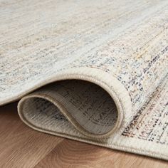 an area rug is laying on the floor with it's end rolled up to reveal a corner