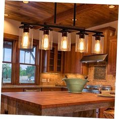 a kitchen island with lights hanging from it's ceiling and wooden cabinets in the background