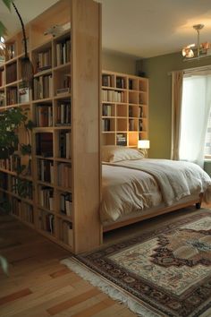 a bed sitting next to a tall book shelf filled with books on top of a hard wood floor