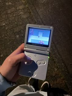 a person is holding an old gameboy in their left hand and playing it on the screen