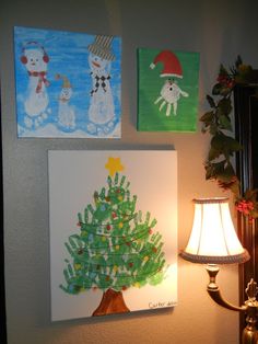 some paintings are hanging on the wall next to a lamp and a christmas tree with snowmen