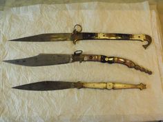 three old knives sitting on top of a white piece of paper next to each other