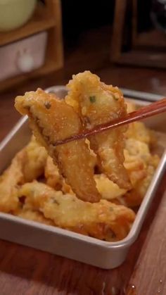 some fried food in a white container with chopsticks sticking out of the top