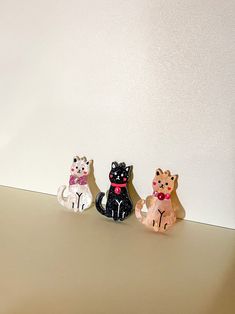 three small figurines of cats sitting on a counter top next to each other