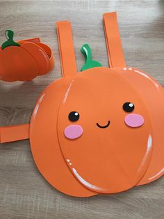 an orange paper plate with a face and two pumpkins on the table next to it