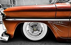 an orange and white classic car parked in a parking lot