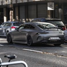 a grey car parked on the side of a road next to other cars and bicycles