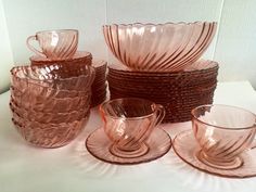 an assortment of pink glass dishes and cups