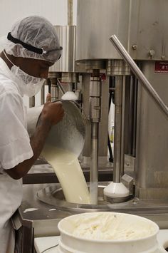 a man pouring milk into a bowl on top of a machine in a kitchen area