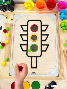 a child's hand is playing with a wooden toy traffic light and other toys