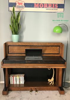 a wooden desk with a laptop on top of it next to a potted plant