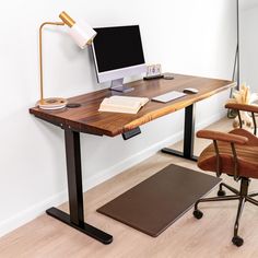 a desk with a computer on it next to a brown chair and rug in the corner