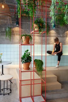 a woman sitting on top of a set of stairs next to potted plants