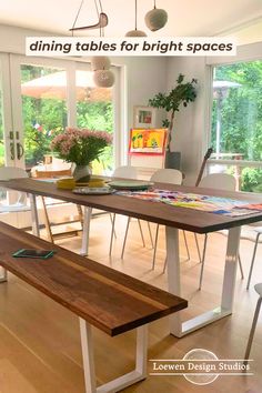 Dining table and bench set made from walnut tabletop and white steel legs shaped like an angle U in a spacious dining room with large windows that look out onto greenery during the day. There are a lot of miscellaneous items on the table and bench like iPad, flower vase, and plates. Airy Dining Room, Wood Rectangle Dining Table, Rustic Wood Bench, Dining Table And Bench, Wood Dining Tables, Dining Room Design Modern, Family Dining Rooms, Hardwood Table, Dining Table Wood