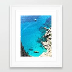 an aerial view of the blue water and rocks in front of a white framed wall