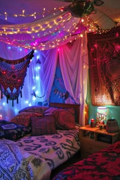 a bed room with two beds covered in blankets and lights hanging from the headboard