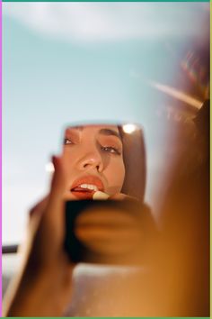 a woman taking a selfie with her cell phone in front of her face and looking at the mirror