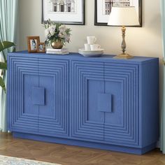 a blue sideboard with two pictures on the wall above it and a lamp next to it