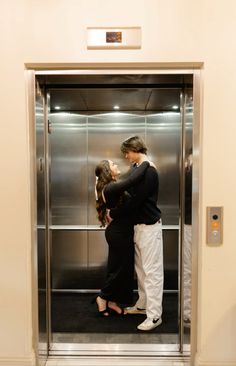 two people are kissing in an elevator with their arms around each other as they stand next to each other