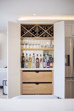 an open cabinet with bottles and glasses on it