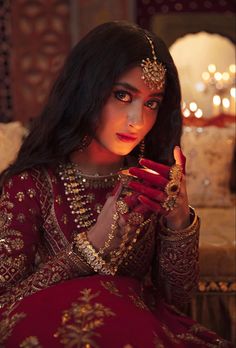 a woman with dark hair wearing a red and gold outfit holding a ring in her right hand