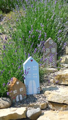 two small houses made out of cardboard sitting in the middle of some rocks and flowers