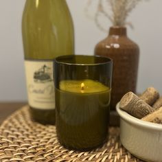 there is a candle and some wine bottles next to each other on a wicker place mat