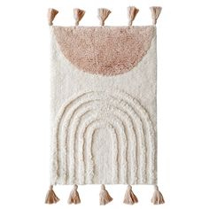 a white and pink rug with tassels on the bottom, an orange circle in the middle