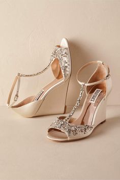 a pair of white high heeled shoes with crystal embellishments on them