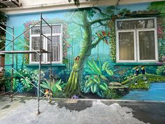 a mural painted on the side of a building in front of a tree with birds perched on it