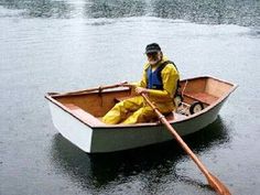 a man in a yellow rain suit is rowing a boat on the water with a oar