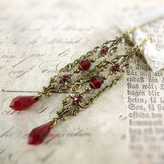 "Romantic blood red Swarovski crystals and antiqued brass filigree with an elegant Gothic design. The filigrees are connected with dangling chain and embellished with matching Swarovski crystal stones. These earrings are extra long and dangly. --------------------------------------------------------------------------------------------- Dimensions and details: - From the top of the ear wire to the bottom of the earrings, they measure approximately 3 1/4\" inches (83mm) - Beads, pearls, teardrops, Red Filigree Dangle Jewelry, Red Dangle Filigree Jewelry, Gothic Pierced Jewelry For Wedding, Red Antique Finish Jewelry Gift, Red Antique Finish Jewelry As Gift, Red Antique Finish Jewelry For Gift, Handmade Gothic Wedding Earrings, Red Jewelry With Antique Finish As A Gift, Elegant Red Chandelier Earrings With Intricate Design